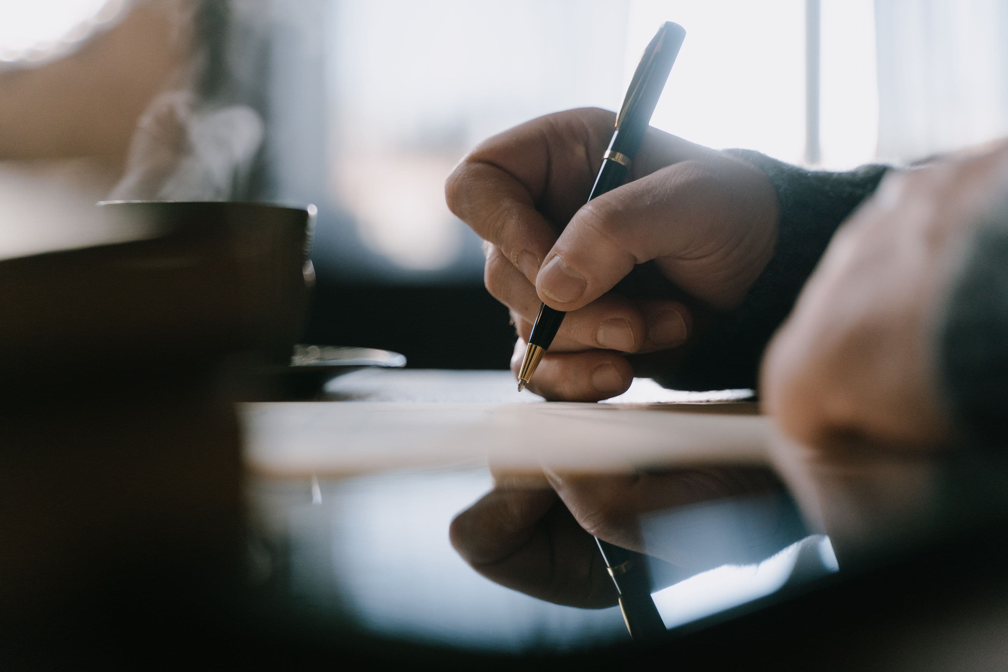 Close-up of a hand signing a document at a desk